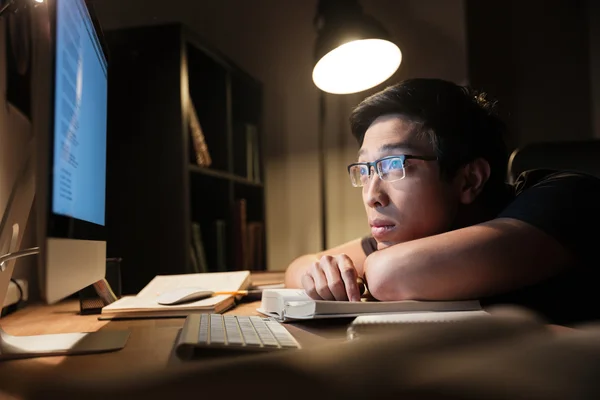 Втомився нудний чоловік вчиться за допомогою книг і комп'ютера вночі — стокове фото
