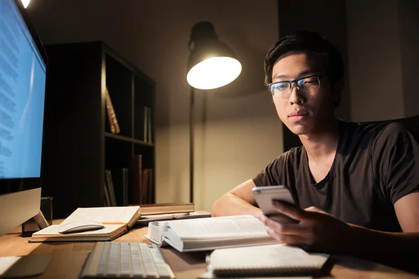 Bonito homem estudando e usando smartphone à noite — Fotografia de Stock