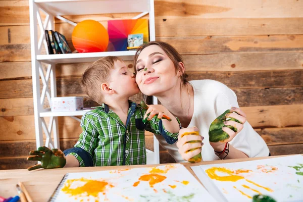Little son kissing mother and having fun using paints