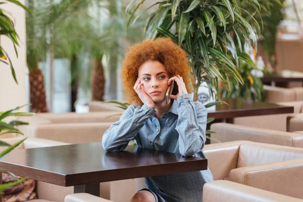 카페에서 휴대 전화에 잠겨있는 곱슬 여자 — 스톡 사진