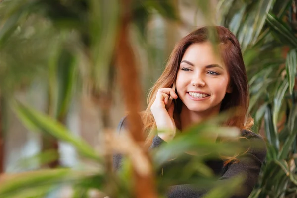 緑の植物の近くのカフェで携帯電話で話している女性 — ストック写真