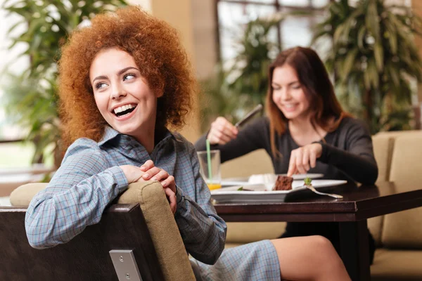 Dos mujeres alegres sentadas en la cafetería y riendo juntas —  Fotos de Stock