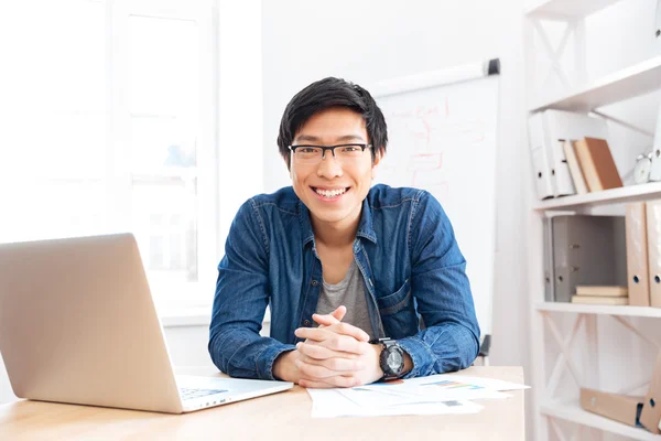 Cheerful businessman working with laptop on workplace