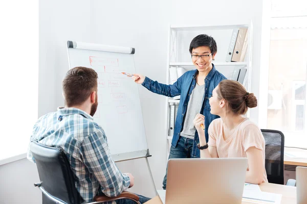 Smilling man making presentation to his colleagues and using flipchart — Stock Photo, Image
