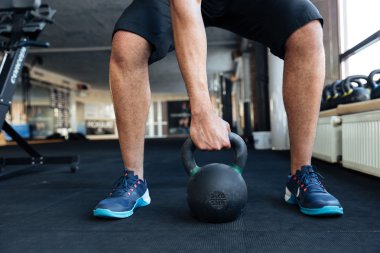 Onun iş salonunda kettlebell kullanarak vücut geliştirmeci