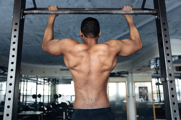 Shirtless fitness man doen maag oefeningen op een horizontale balk — Stockfoto