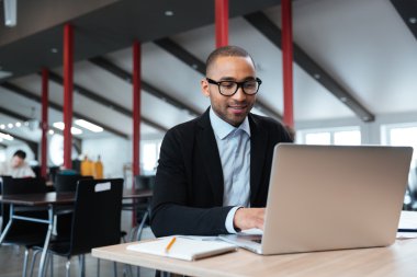 Yakışıklı işadamı dizüstü kullanarak çalışma