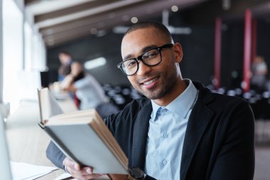 Yakışıklı genç iş adamı onun masasında kitap okuma