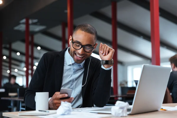 Hombre de negocios sonriendo y mensajes de texto en el teléfono inteligente — Foto de Stock