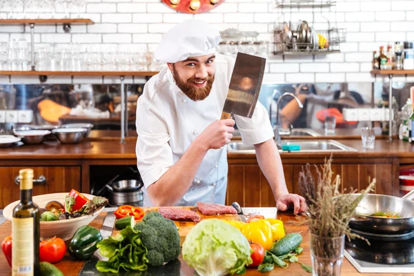 微笑着厨师厨师用菜刀刀切肉和蔬菜 — 图库照片