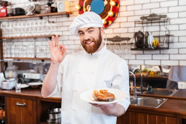 Koch hält Lachssteak auf Teller und zeigt OK-Geste — Stockfoto