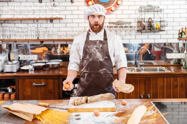 Ekmek kesme ve yumurta mutfak üzerinde tutarak sürpriz baker — Stok fotoğraf