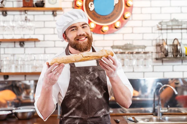 Padeiro alegre mostrando pão na cozinha — Fotografia de Stock