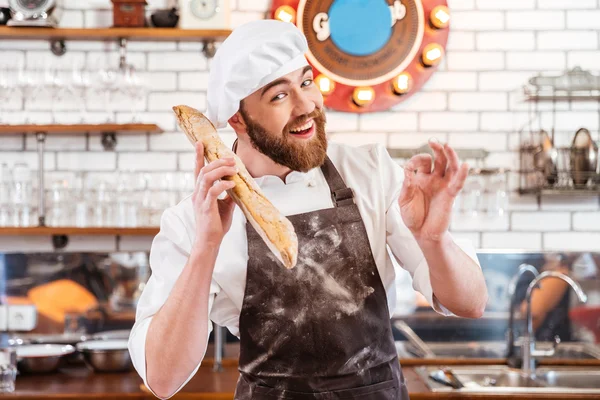 Ekmek basılı tutup ok işaret gösteren mutlu baker — Stok fotoğraf