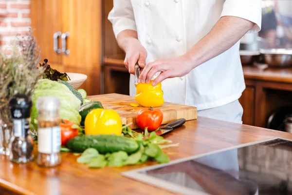 Chef cocinero cortar pimiento amarillo en la cocina — Foto de Stock