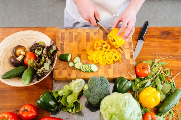 Cocinero haciendo slald y cortando verduras frescas en la mesa — Foto de Stock