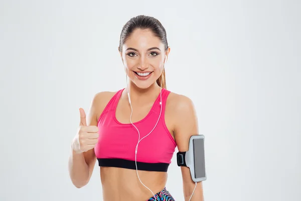 Mulher de fitness sorridente com fones de ouvido mostrando polegar para cima — Fotografia de Stock