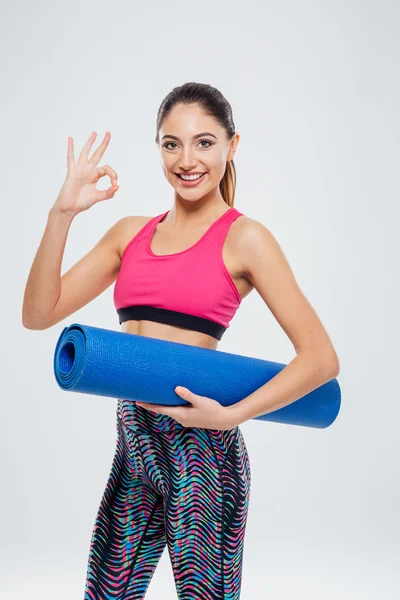 Vrouw houdt van yoga mat en tonen ok teken met vingers — Stockfoto