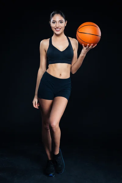 Ayakta ve basketbol topu tutan mutlu güzel genç fitness kız — Stok fotoğraf