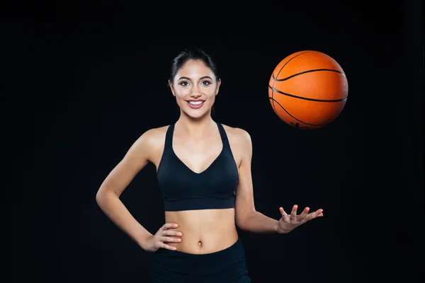 Cheerful attractive young sportswoman throwing up orange basketball ball — Stock Photo, Image