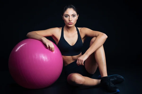 Beautiful young fitness woman sitting and posing with purple fitball — Stock Photo, Image
