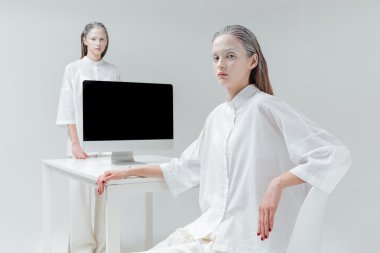 Oturma ve tablo ile bilgisayar, yanında duran iki kadın pc