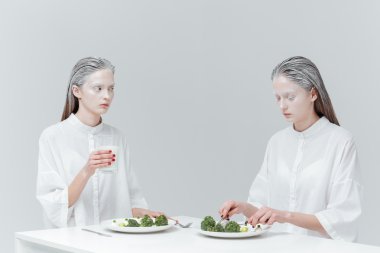 İki kız masada yemek yiyor