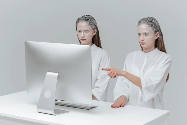 Kaksi kosmista naista istuu tietokoneella. — kuvapankkivalokuva