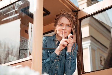 Telefon kutusu ve sessizlik işaret gösteren mutlu kadın