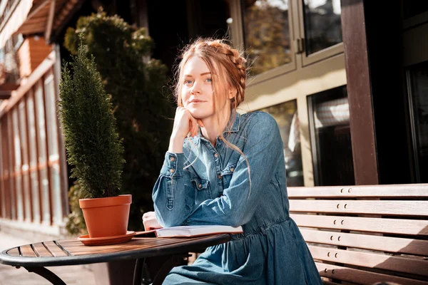 Mulher pensativo sentado e lendo um livro no café ao ar livre — Fotografia de Stock