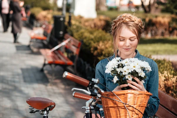 Charmante Frau mit Fahrrad hält Blumenstrauß auf Bank — Stockfoto