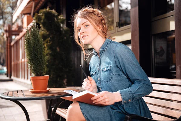 Mulher bonita sentada e escrevendo em notebook ao ar livre — Fotografia de Stock