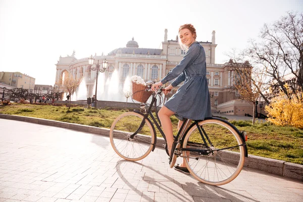 Mulher feliz andando de bicicleta perto do teatro — Fotografia de Stock