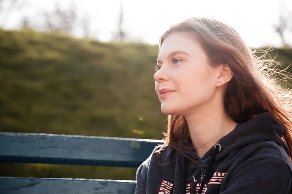 Hübsche junge Frau sitzt auf der Bank im Park — Stockfoto