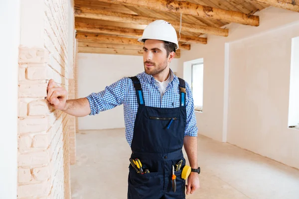 Jovem construtor pensando em algo dentro de casa — Fotografia de Stock