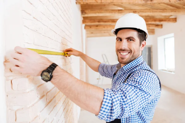 Trabajador de la construcción usando cinta métrica en una casa nueva —  Fotos de Stock