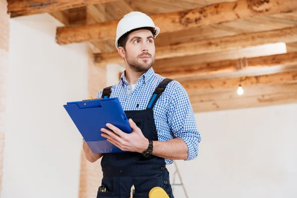 Erbauer in Hardhat mit Klemmbrett und Bleistift drinnen — Stockfoto