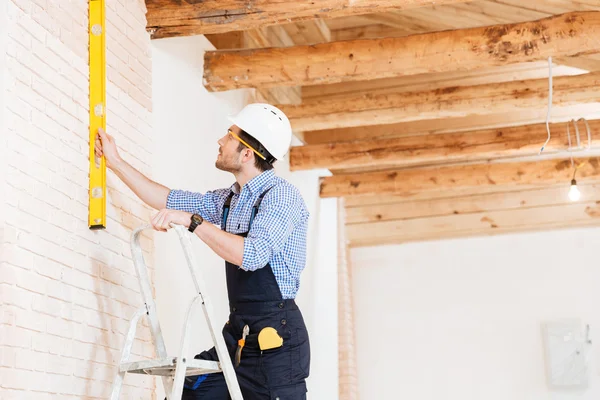Bauarbeiter, der die Konstruktionsebene nutzt und auf der Leiter steht — Stockfoto