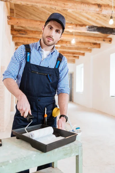 Trabalhador do construtor com um rolo de pintura dentro de casa — Fotografia de Stock