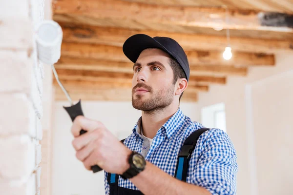 Close-up portrait of a builder worker painting wall indoors — Stock Photo, Image