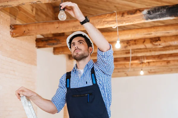 Bauarbeiter befestigt Steckdose mit Leiter im Haus — Stockfoto