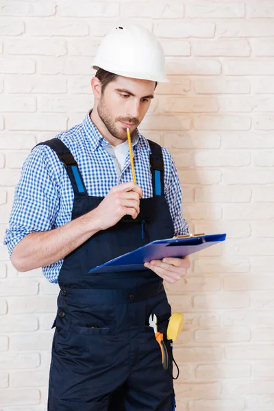 Trabalhador da construção pensando em algo usando prancheta — Fotografia de Stock