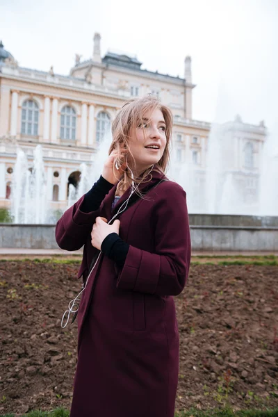 Γυναίκα στα ακουστικά στέκεται και να ακούτε μουσική σε εξωτερικούς χώρους — Φωτογραφία Αρχείου