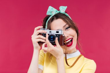 Gülümseyen çekici genç kadın eski kamera ile fotoğraf çekmek