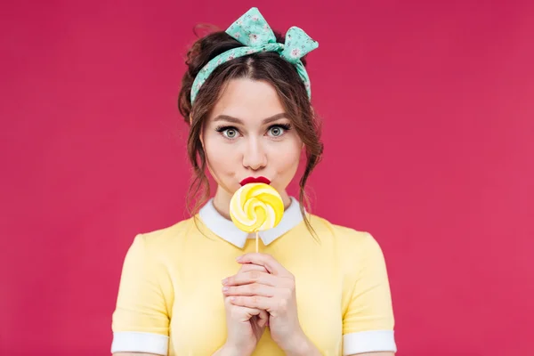 Retrato de una hermosa chica pinup comiendo piruleta amarilla dulce —  Fotos de Stock