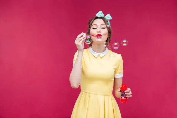 Aantrekkelijke pinup meisje in gele jurk zeepbellen blazen — Stockfoto
