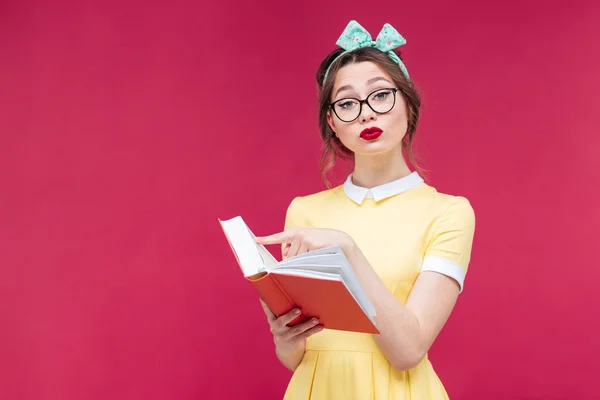 Komoly fiatal nő a szemüveg álló és olvasott egy könyvet — Stock Fotó