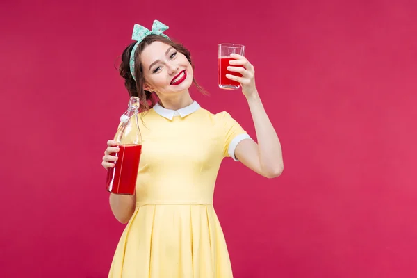 ボトルとジュースのグラスを持つ笑顔かわいいピンナップの女の子 — ストック写真