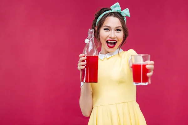 Feliz chica hermosa pinup que le da un vaso de jugo — Foto de Stock