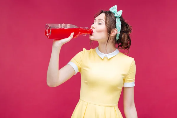 Vacker ung kvinna stående och dricka saft från flaskan — Stockfoto